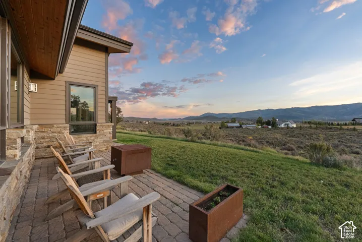 Expansive paved patio with stacked stone accents, siding exterior, and a wood-finish soffit
