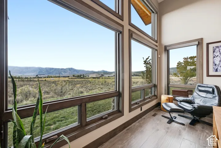 Expansive window wall with dark wood-finish framing, wood-finish flooring, and high ceilings