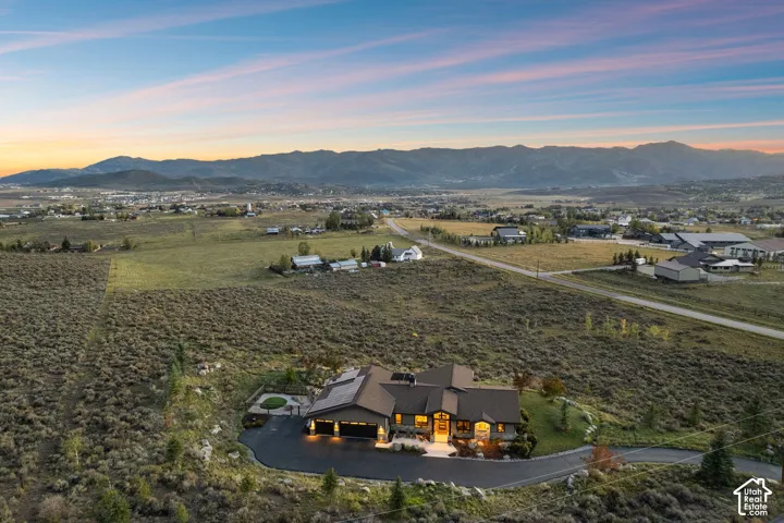 Expansive lot featuring a contemporary residence with a dark-pitched roof, attached garage, and paved driveway