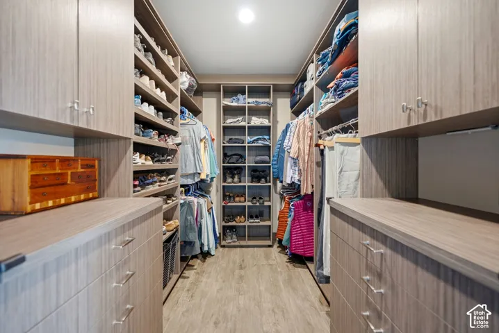 Custom closet system featuring wood-finish flooring, built-in shelving, integrated drawers, and hanging storage
