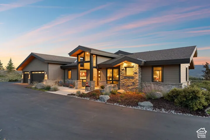 Contemporary architectural design with multiple rooflines, stone and siding exterior, large windows, and an attached two-car garage