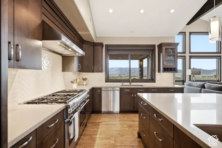 Dark wood-finish cabinetry with silver-tone hardware, a herringbone pattern tile backsplash, and light-tone countertops