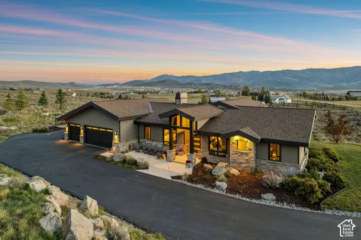 Expansive residential property featuring a multiple-car garage, stone and siding exterior, large windows, and a paved driveway