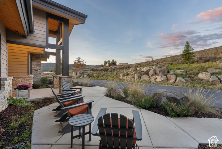 Covered porch with wood-clad ceiling, stone column accents, and natural wood siding