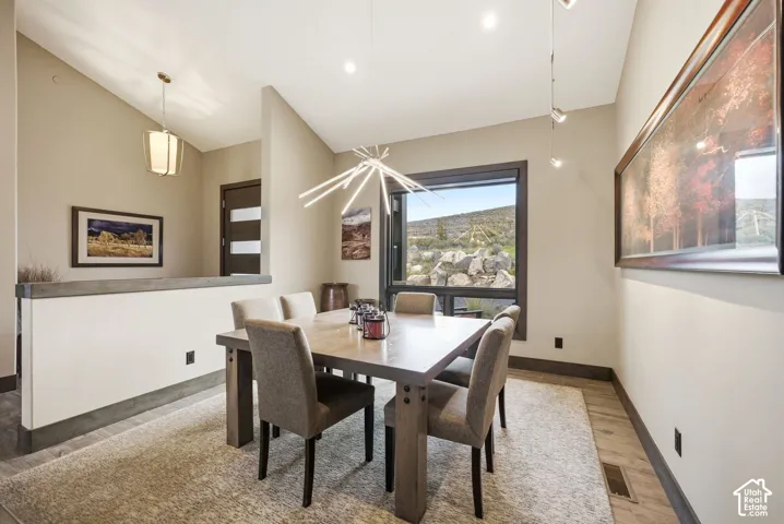Modern dining area with a large picture window, a contemporary linear chandelier, and recessed lighting