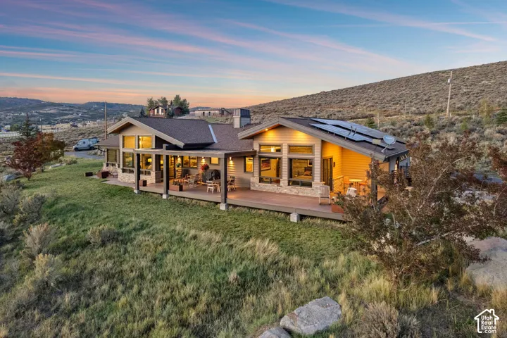 Ranch-style residence featuring a covered deck, stone accents, horizontal siding, and multiple solar panels