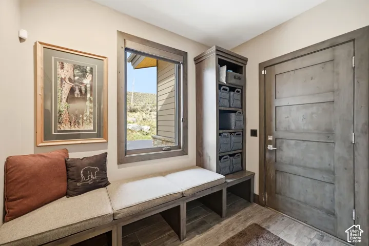 Built-in bench seating with upholstered cushions, integrated storage cubbies, a wood-framed window, and a paneled wood-finish door with brushed nickel hardware