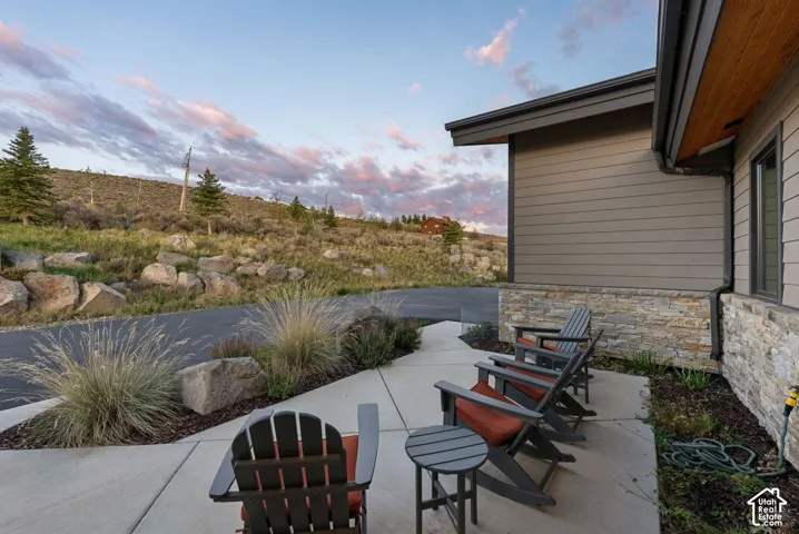 Exterior featuring horizontal siding, stone facade, covered patio, and concrete hardscaping