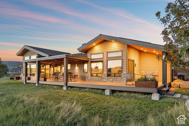 Contemporary exterior architecture featuring a covered deck, an open deck, wood siding, stone accents, and sloped rooflines