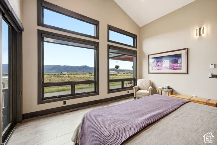 Vaulted ceiling, multiple large windows, light-toned walls, recessed lighting, and light wood-finish flooring