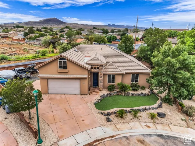 Stucco exterior with stone accents, a tile roof, an integrated garage, and a concrete driveway