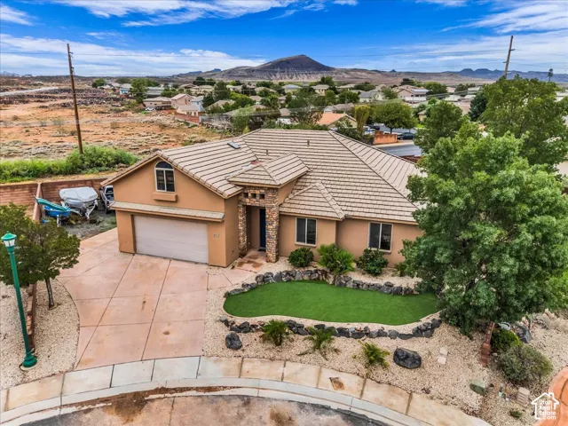 Stucco exterior residence featuring a tile roof, an integrated garage, and a concrete driveway