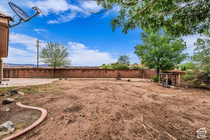Expansive backyard with a concrete patio and a perimeter privacy wall