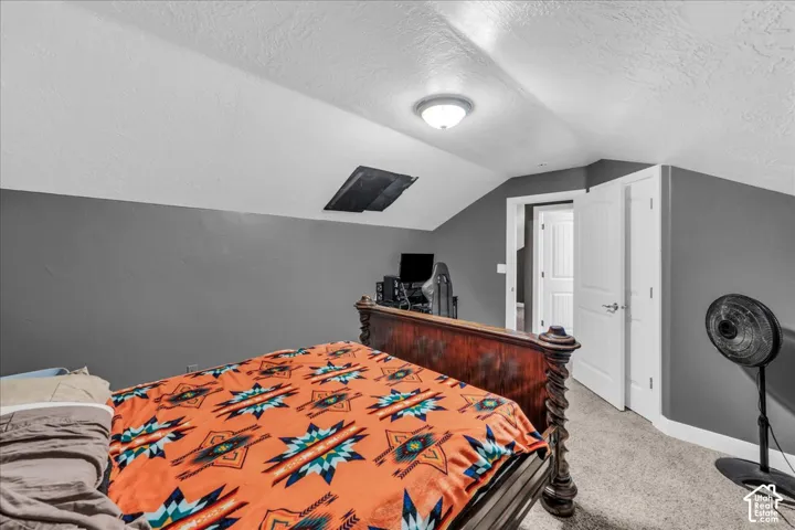 Carpeted flooring, vaulted ceiling, recessed lighting, and a white paneled door