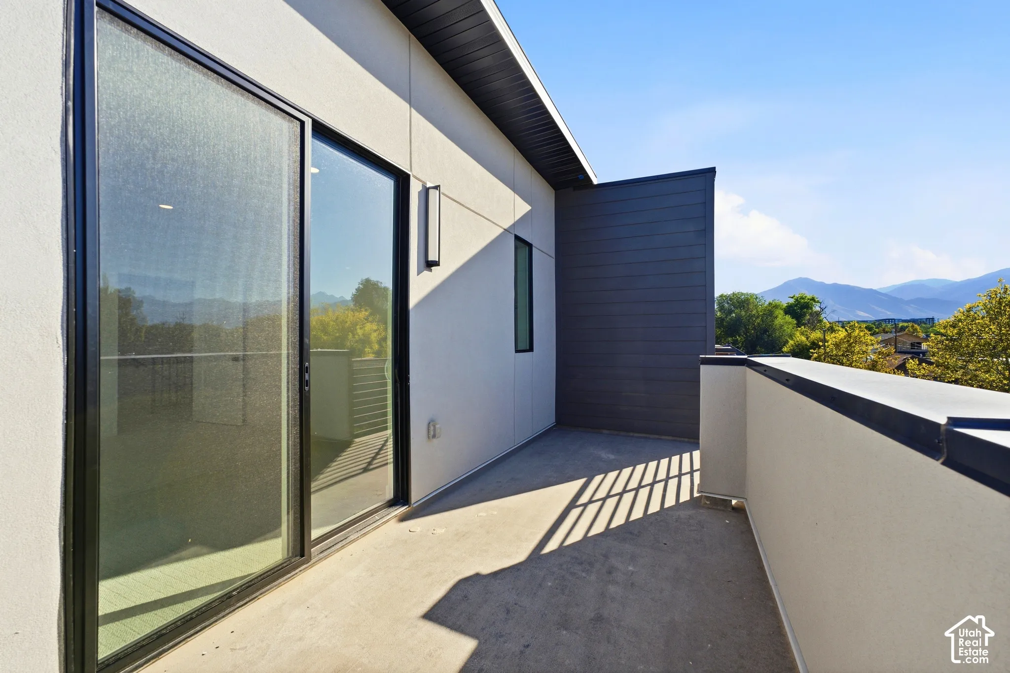 Private exterior balcony with modern wall sconce, and mountain scenery