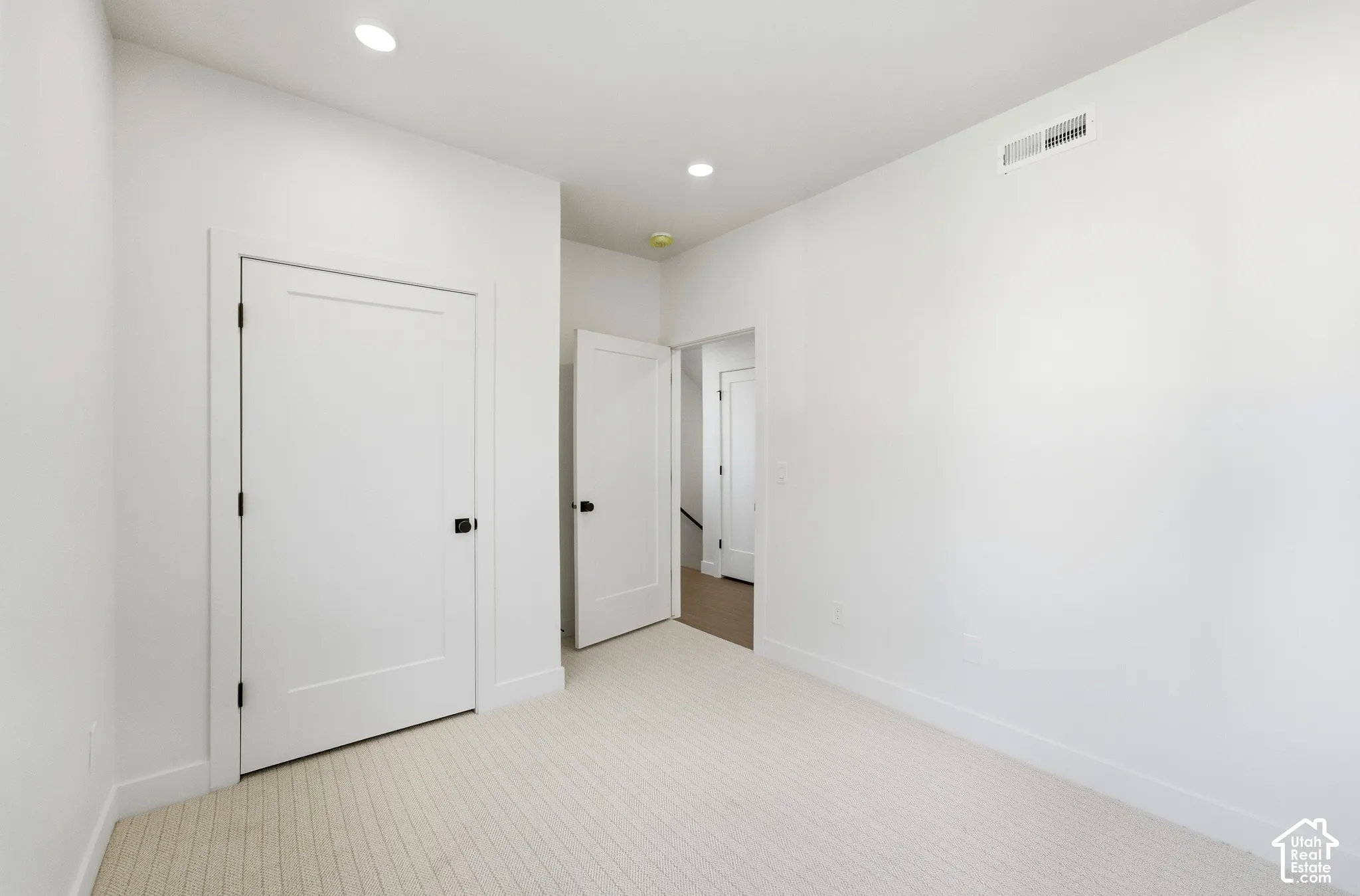 Recessed lighting, wall-to-wall carpeting, crisp white walls, contemporary flat-panel doors, matte black door hardware