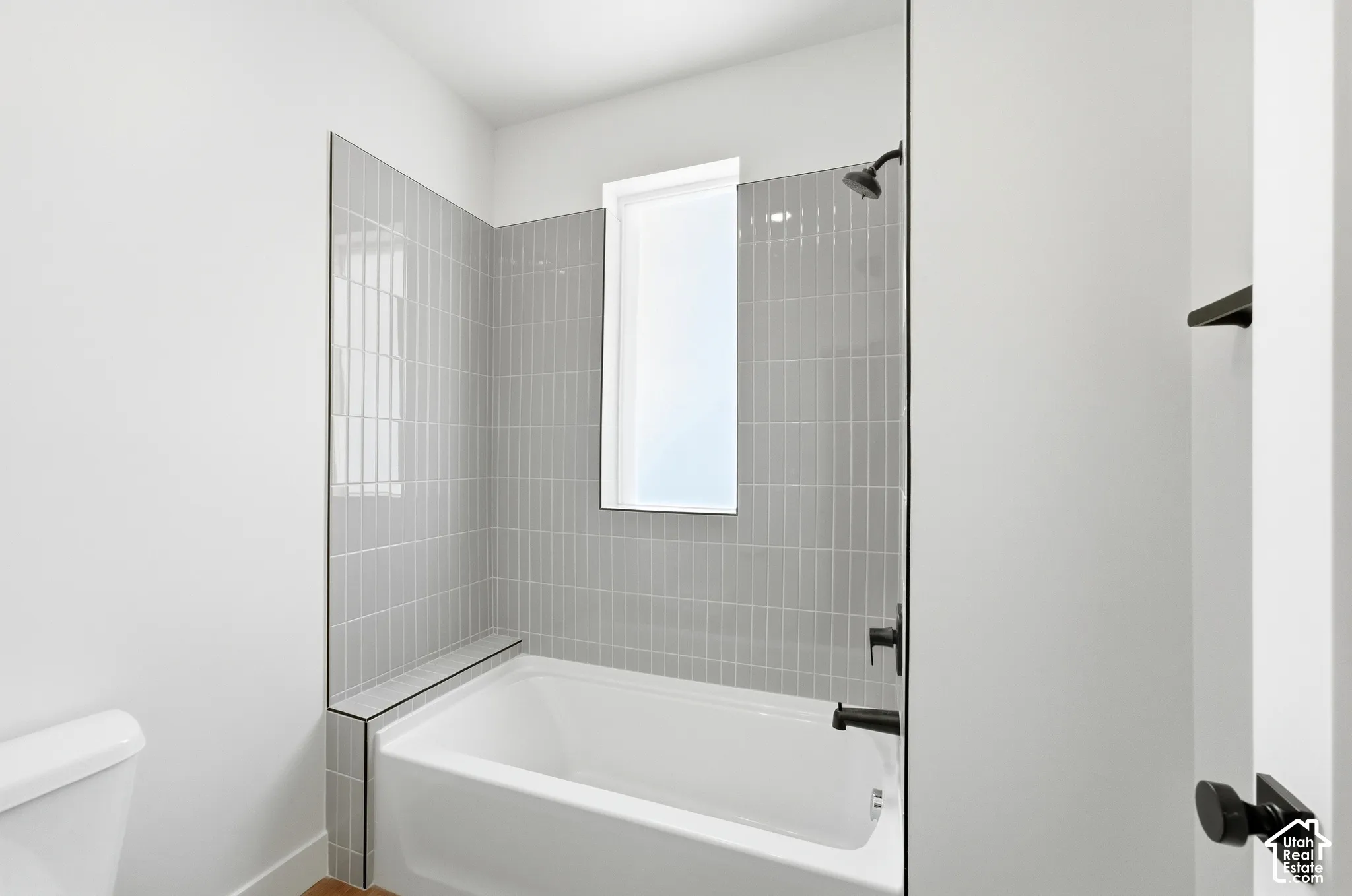 Bathtub with light gray vertical tile surround and matte black fixtures