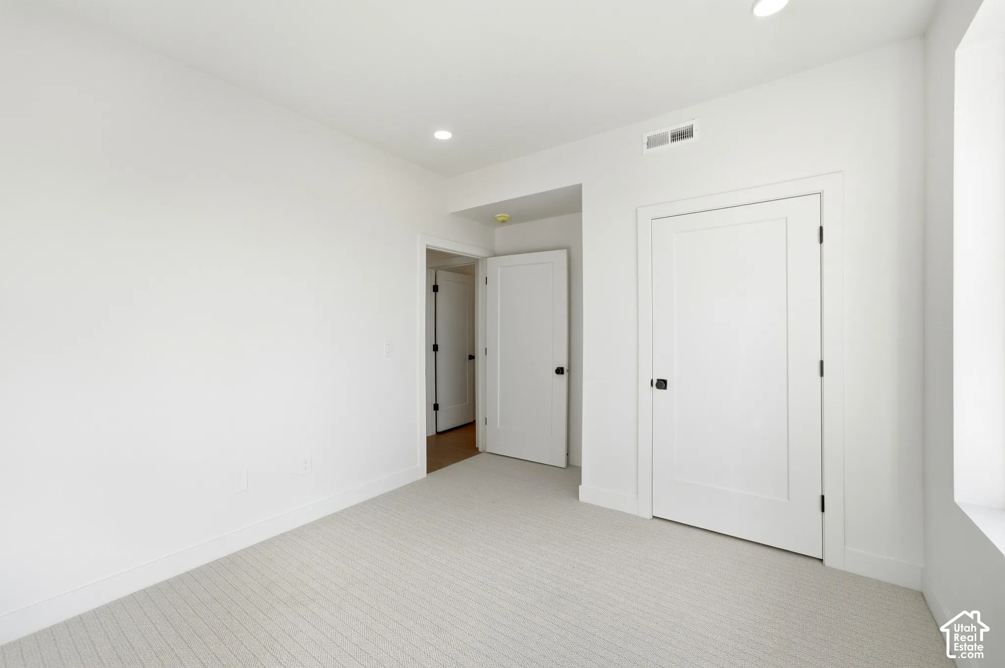 Recessed lighting, light-toned carpeting, white walls, and bright white trim