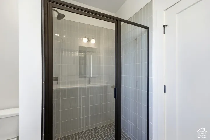 Glass-enclosed shower with black framing and vertical subway tile surround
