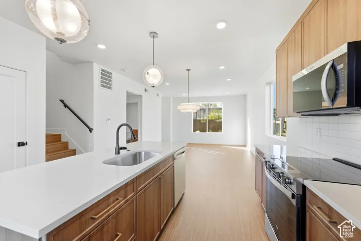 Open-concept kitchen with a large central island, stainless steel appliances, wood-finish cabinetry, and recessed lighting