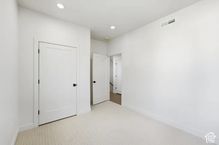 Recessed lighting, wall-to-wall carpeting, crisp white walls, contemporary flat-panel doors, matte black door hardware