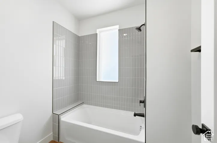 Bathtub with light gray vertical tile surround and matte black fixtures