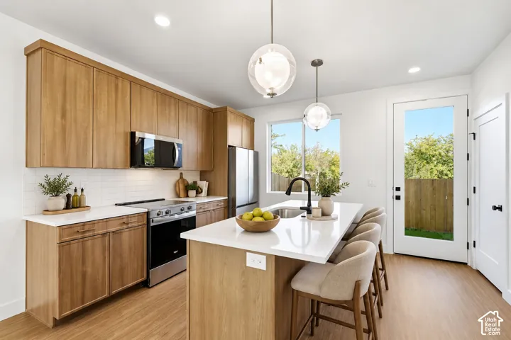 Modern kitchen featuring wood-finish cabinetry, stainless steel appliances, and an island with seating