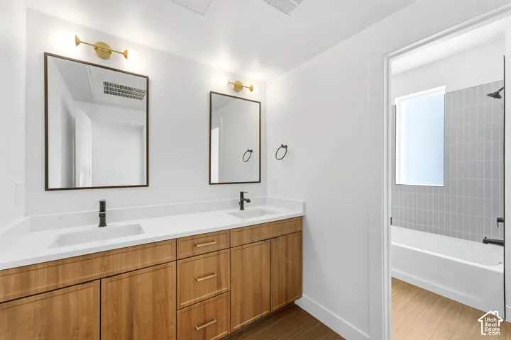 Dual vanity with wood-finish cabinetry, white countertops, and matte black fixtures