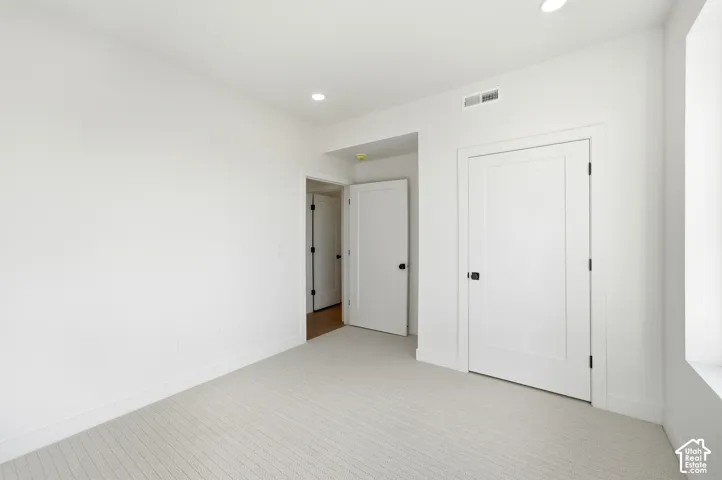 Recessed lighting, light-toned carpeting, white walls, and bright white trim