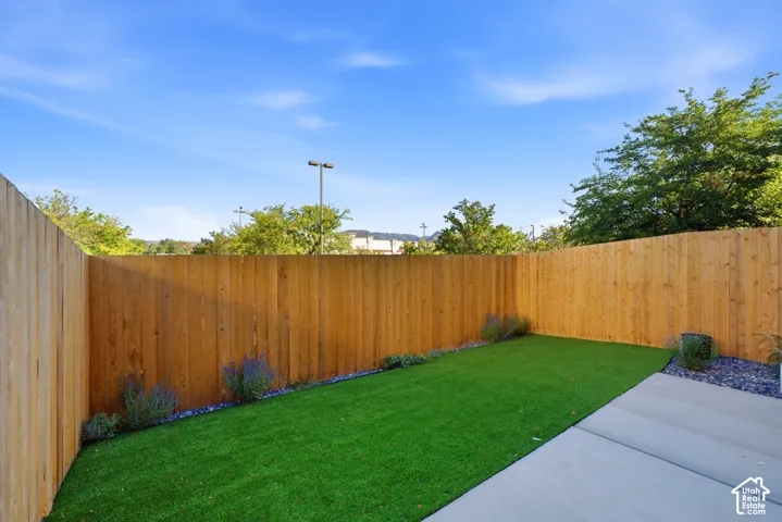 Private outdoor space featuring artificial turf, concrete patio, wood fencing, and perimeter landscaping