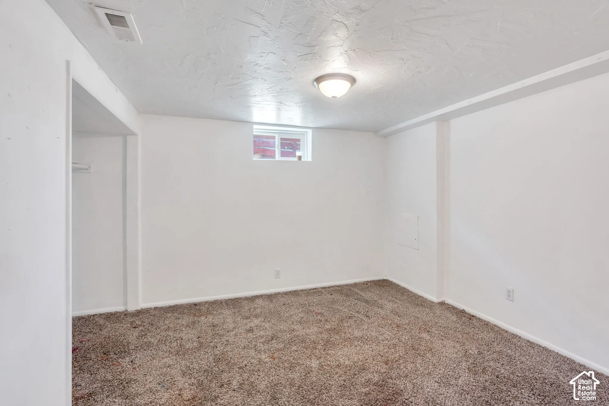 White walls featuring a textured ceiling, flush mount ceiling light, and a single window