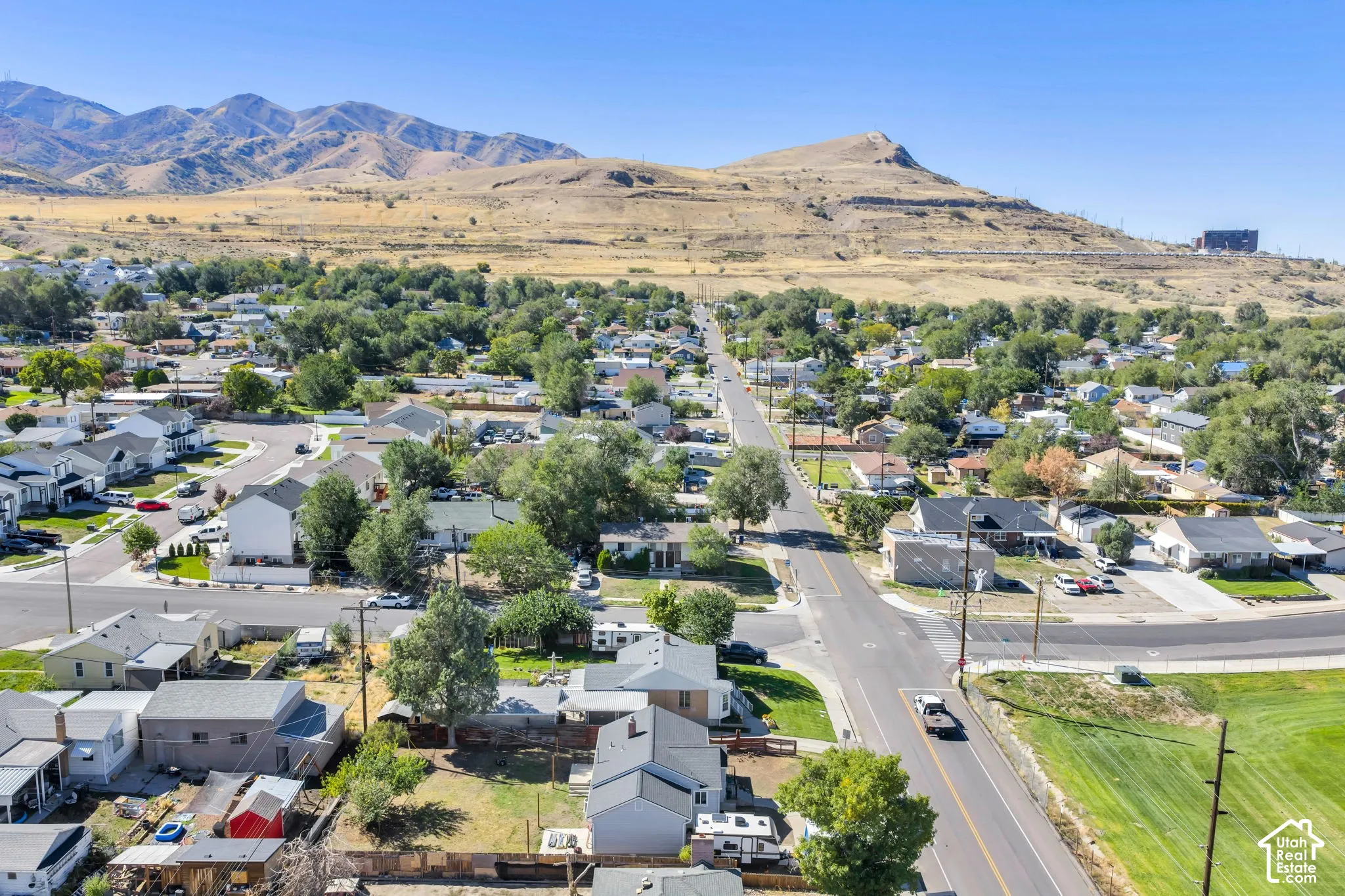 Residential neighborhood with established streets and mature trees, set against a backdrop of distant mountains and hills
