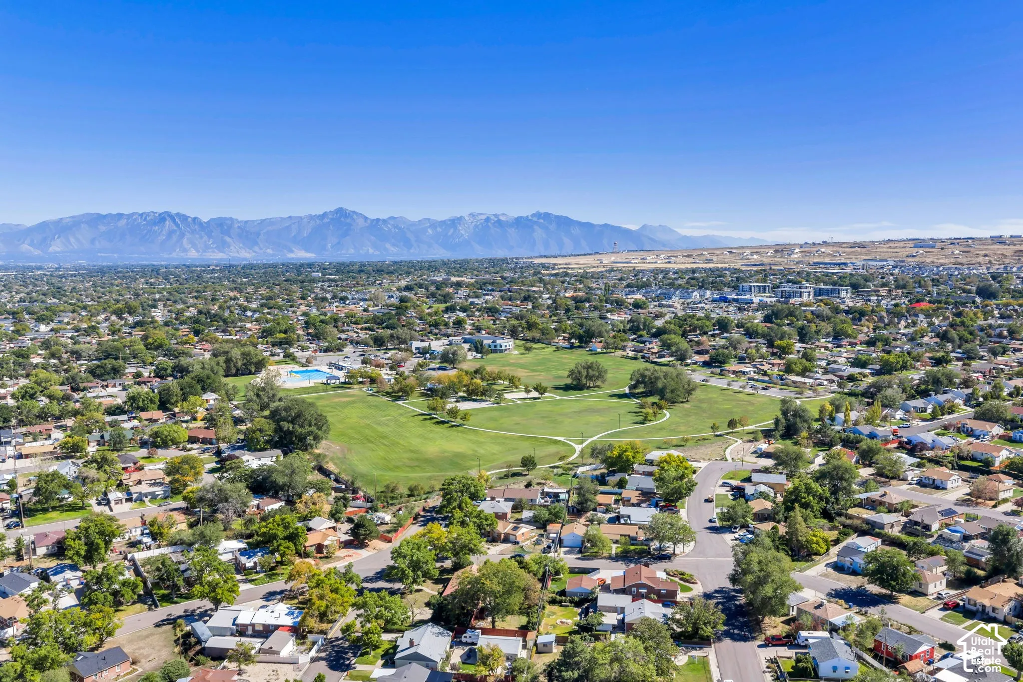 Expansive neighborhood with mature trees, green spaces, and a visible community pool