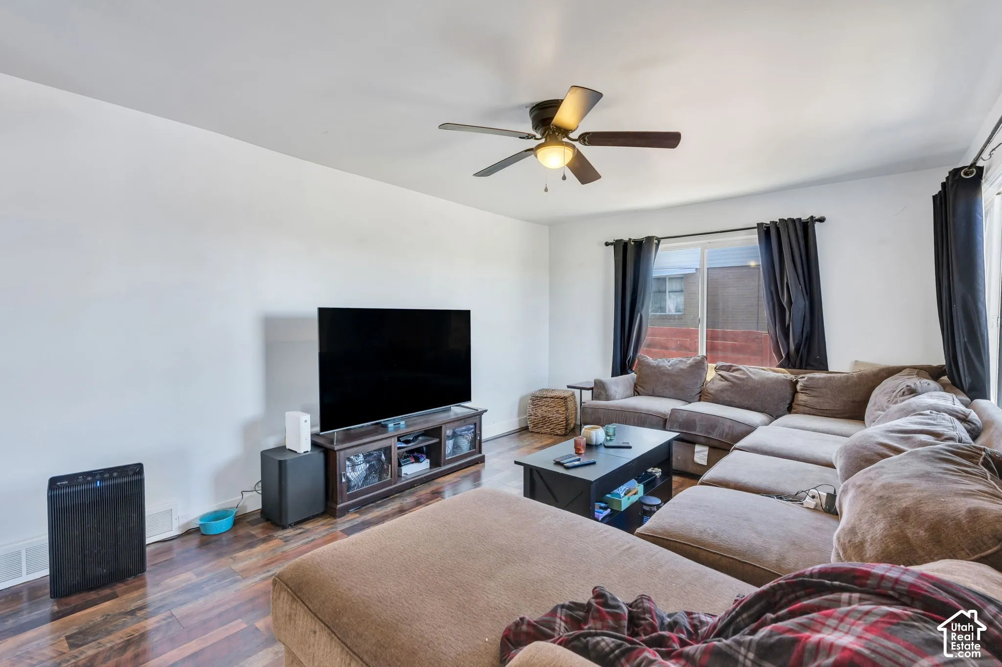 Wood-finish flooring, white wall finishes, and a ceiling fan with integrated lighting