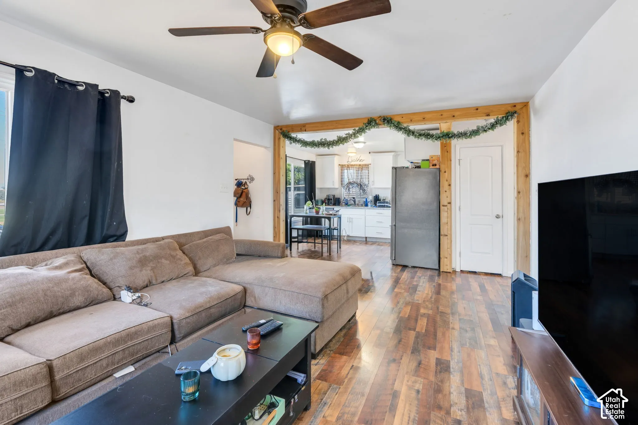 Wood-finish flooring throughout, ceiling fan with integrated lighting, and a white interior door
