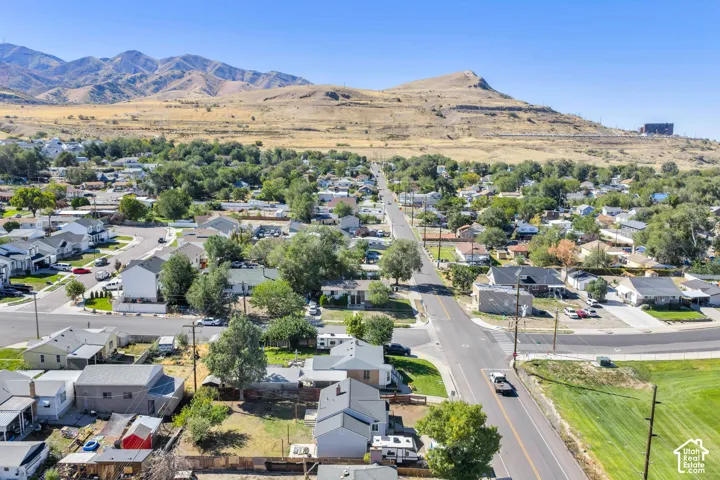 Residential neighborhood with established streets and mature trees, set against a backdrop of distant mountains and hills