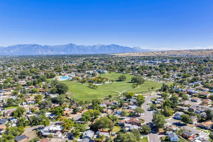 Expansive neighborhood with mature trees, green spaces, and a visible community pool