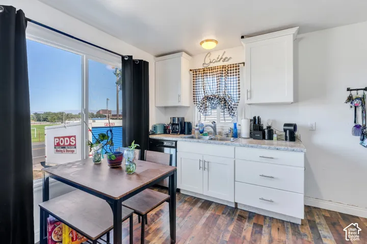 Kitchen featuring white cabinetry, granite-style countertops, stainless steel sink, wood-finish flooring, and a large sliding glass door