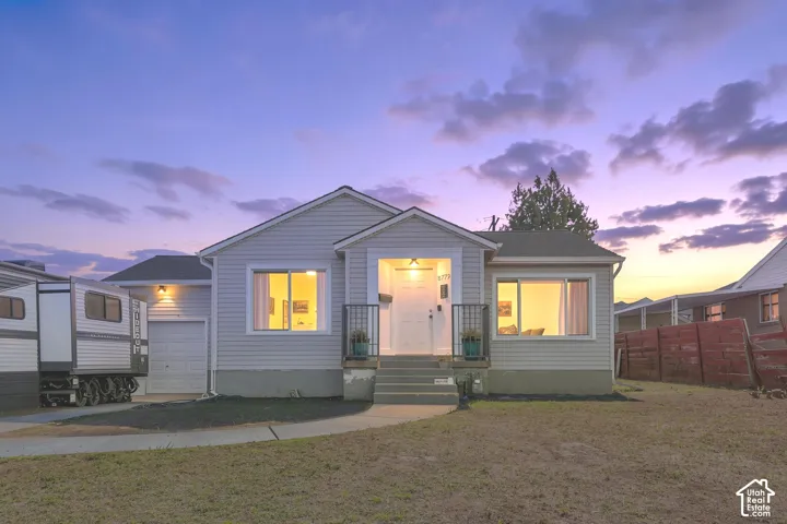 Light gray siding exterior with a covered entry, attached garage, and concrete walkway