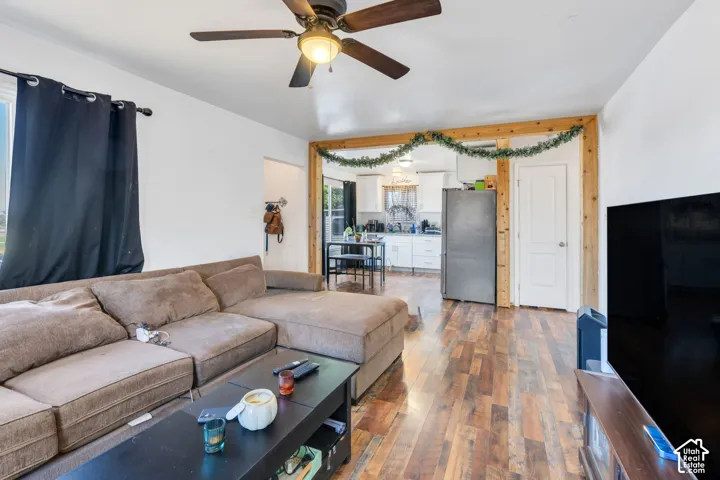 Wood-finish flooring throughout, ceiling fan with integrated lighting, and a white interior door