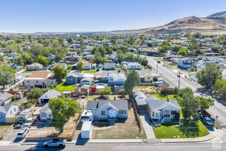 Aerial perspective of a neighborhood with diverse housing styles, mature trees, and a distant mountain backdrop