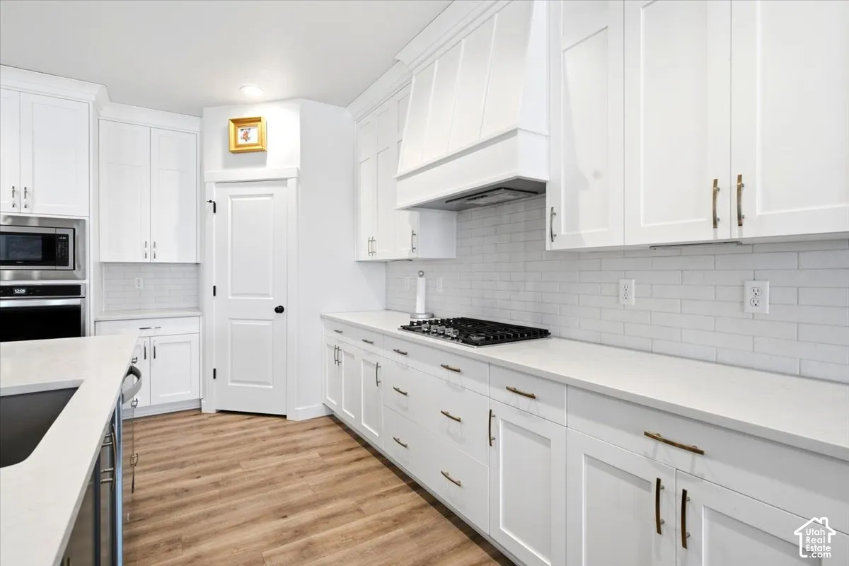 Stainless steel appliances, built-in wall oven, five-burner gas range, and an expansive walk-in pantry with outlets for small appliances
