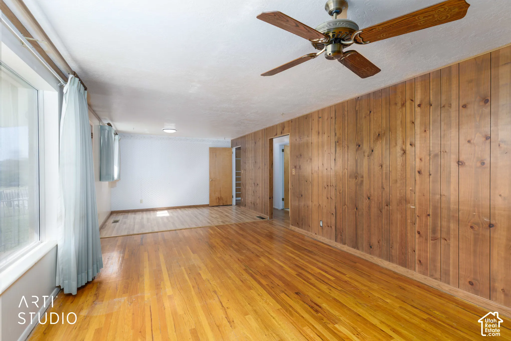 Hardwood flooring extends throughout this expansive room, complemented by a wood panel accent wall