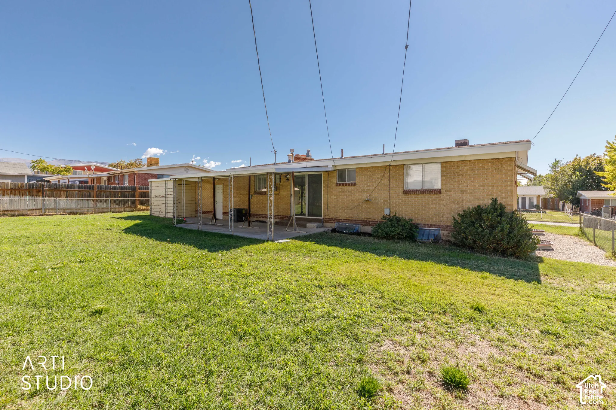 Expansive backyard featuring a brick exterior, covered patio, and a storage shed
