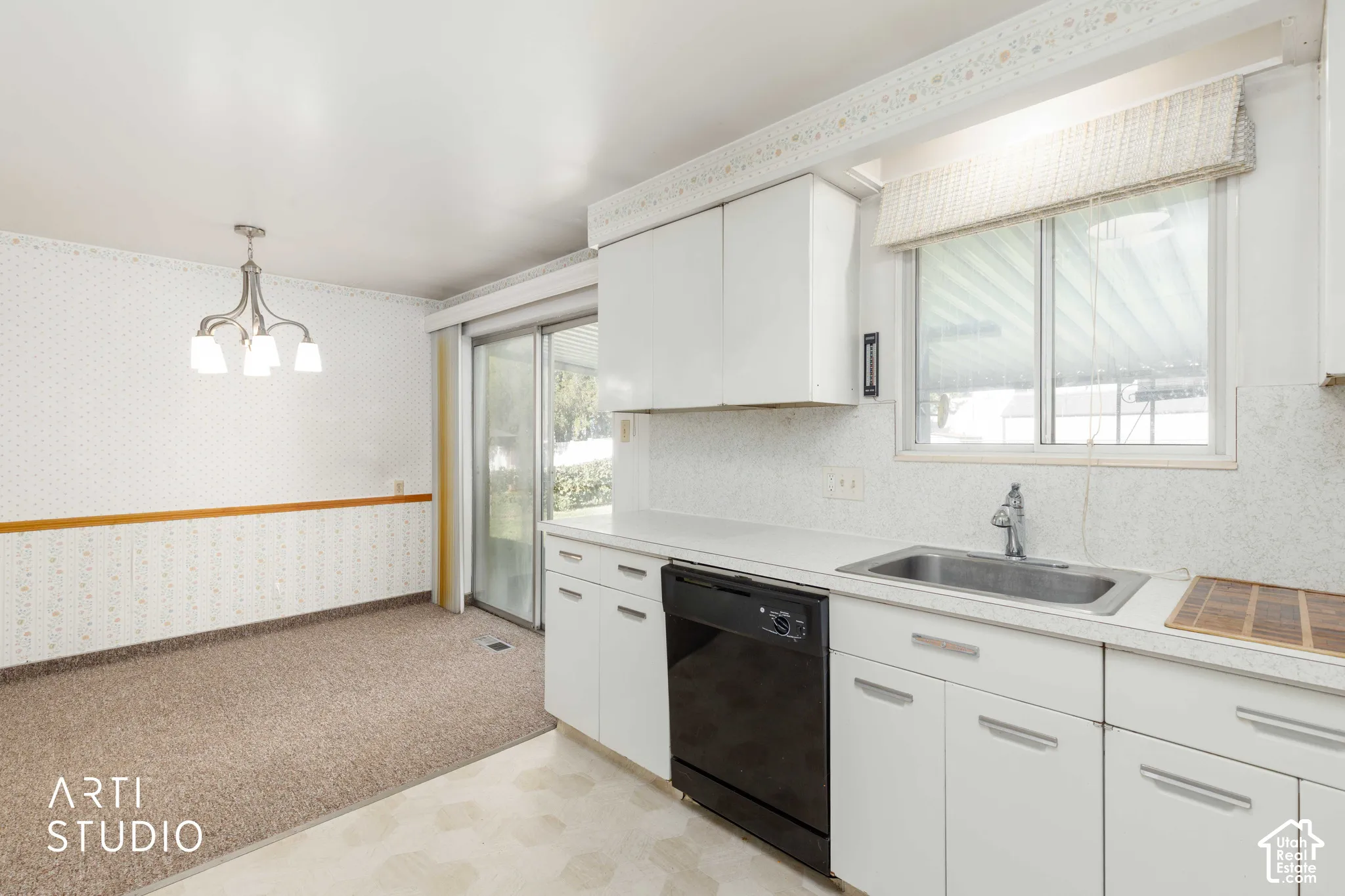 Kitchen featuring white cabinetry and countertops, an integrated stainless steel sink, and a black dishwasher