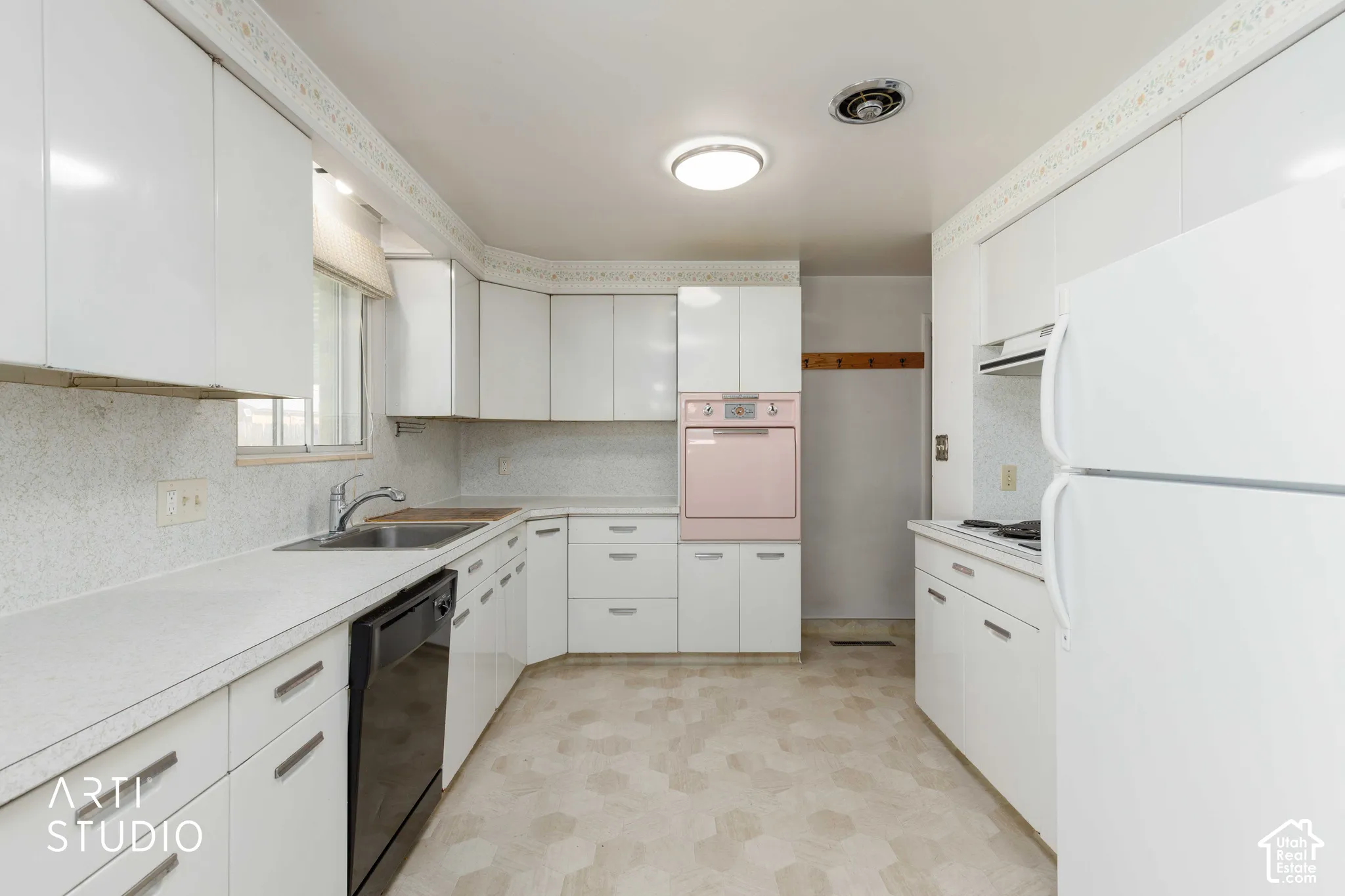 Kitchen featuring white cabinetry, light-toned countertops, a stainless steel sink, and light-colored flooring