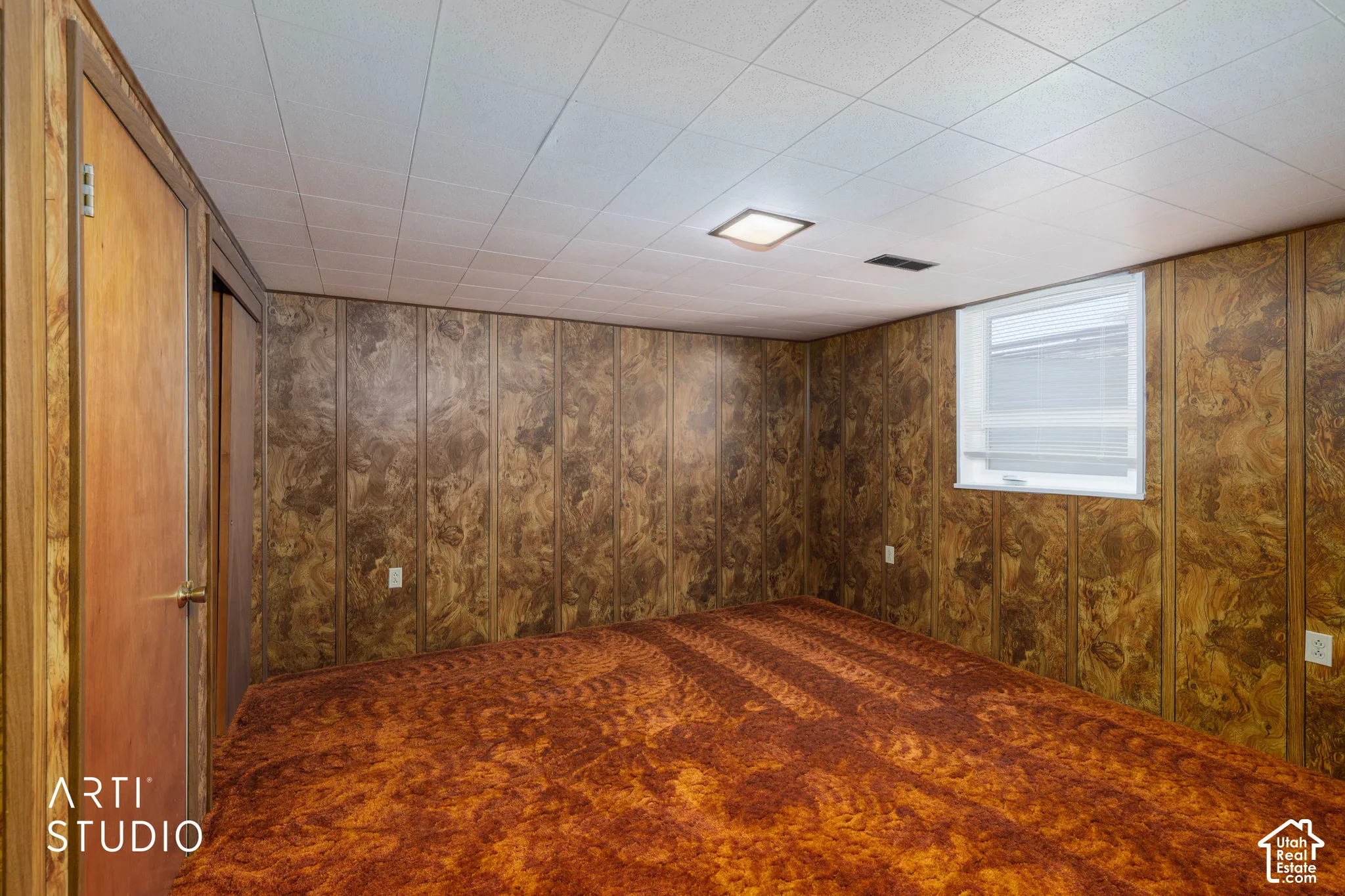 Room featuring wood-finish wall panels and a white grid ceiling