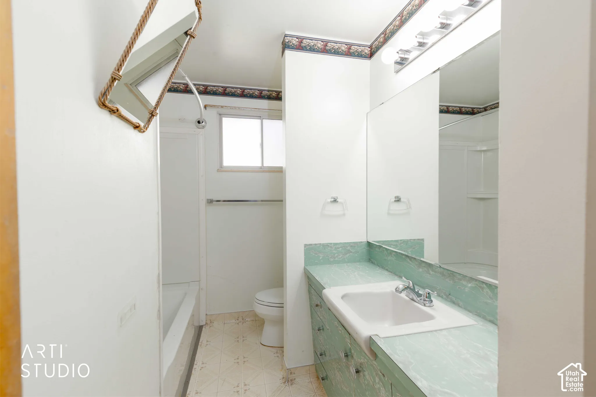 Bathroom featuring a single vanity with an integrated sink, an expansive mirror, a shower-tub combination, and a window