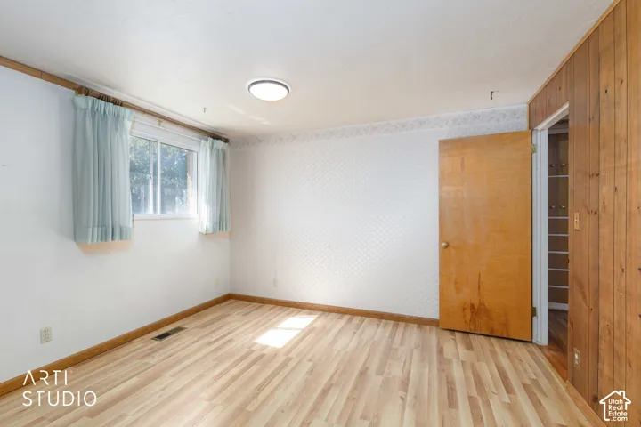 Wood-finish flooring with a white textured wall and wood paneling accents