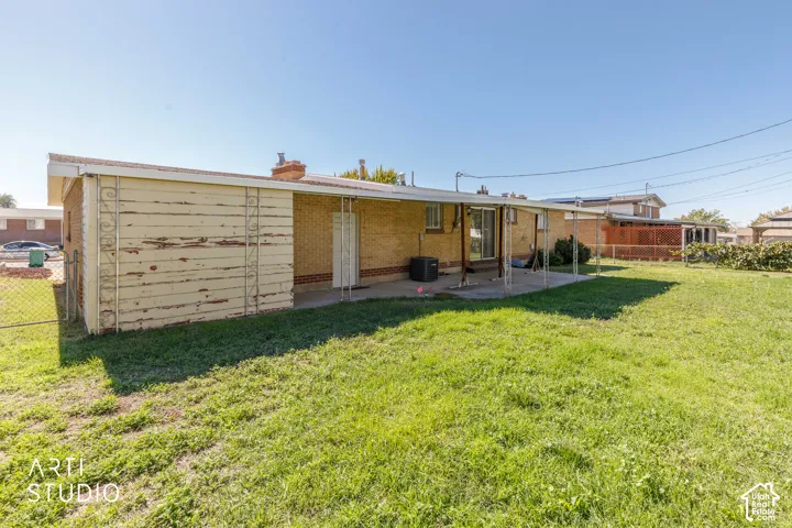Expansive grassy yard with a covered patio and a separate storage structure